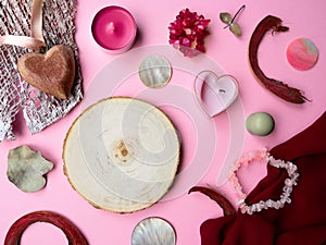 Flat lay tree saw cut,pink,green tone.Textured fabric,semiprecious stone bracelet,candle,leaves,bark pieces,copy space