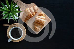 Flat lay two fresh croissants and cup of coffee on dark stone table