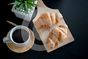 Flat lay two fresh croissants and cup of coffee on dark stone table