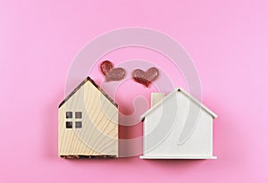 Flat lay of two wooden model houses with red glitter hearts on pink  background. dream house , home of love, strong relationship,