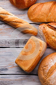 Flat lay various bread loaves on wooden background.