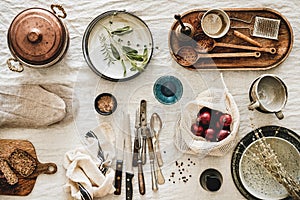 Various kitchen utensils, tablewear and fresh bread over linen tablecloth photo