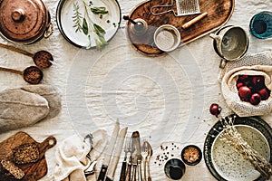 Various kitchen utensils and tablewear over linen tablecloth, copy space photo