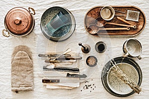 Various kitchen utensils and tablewear over rustic linen tablecloth photo