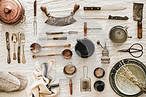 Kitchen utensils and tablewear over linen tablecloth, top view photo
