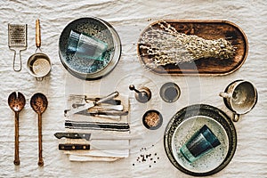 Various kitchen utensils and tablewear over linen tablecloth photo