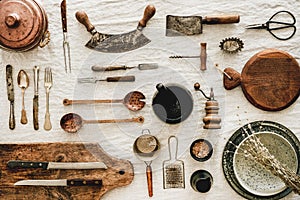 Various kitchen utensils and tablewear over rustic linen tablecloth photo