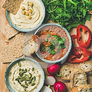 Flat-lay of Vegetarian dips hummus, babaganush, muhammara, square crop