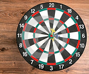 Flat lay view of a dartboard with three darts in the bull`s eye. Well-aimed dart throwing.