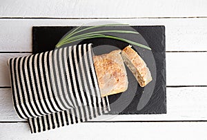 Flat lay view freshly baked homemade wheat flour loaf of bread on black stone serving board .