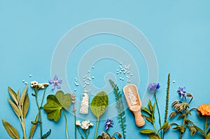 Flat lay view homeopathic medicine pills in jars and spilled around on light blue background.