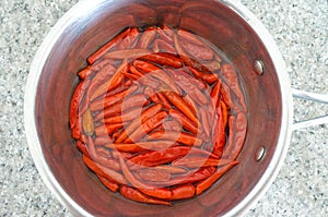 Flat lay view of hot red chillies cooked in a metal pot