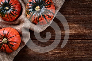 Flat lay view of three pumpkins on jute bag. Old wooden background or table top