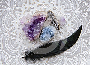 Flat lay view of various crystal geodes amethyst  celestite. With black glowing bird feather. photo