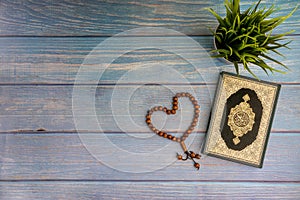 Flat lay view of vase, tasbih or rosary beads and Holy book of Al Quran