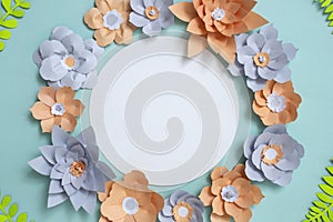 Flat lay of vintage round card frame, color paper flowers design on blue background. Top view, copy space, floral artFlat lay of v