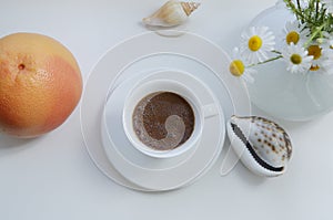 Flat lay, white cup of coffee and orange grapefruit and white daisy flowers on a white background with design elements