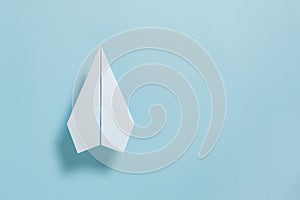 Flat lay of white paper plane on pastel blue color background