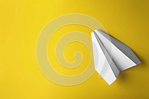 Flat lay of white paper plane on pastel yellow color background
