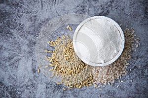 Flat lay of White rice flour in wooden bowl, from whole rice Thai grains with rice ears isolated on stone background,