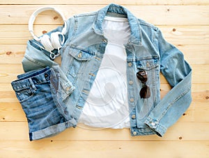 Flat lay, White tshirt mockup denim jacket jeans and headphones on brown wooden background. Template