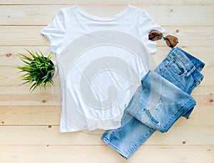 Flat lay, White tshirt mockup jeans and sunglasses on brown wooden background. Template