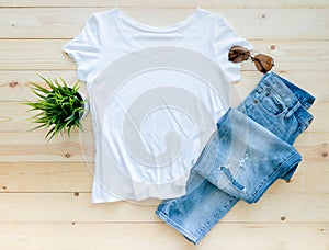 Flat lay, White tshirt mockup jeans and sunglasses on brown wooden background. Template photo