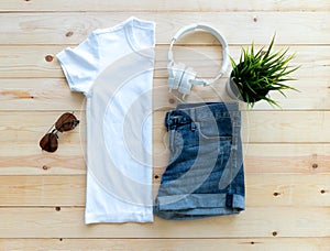 Flat lay White tshirt mockup short jeans headphones and Sunglasses on brown wooden background. Template