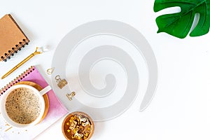 Flat lay of white working table place background with cup of coffee putting on it. Top view glasses, leaf, golden paper binder