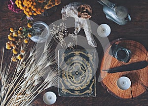 Flat lay of witch`s altar space with a grimoire vintage book from 1837 and other various items - dried flowers nature elements,