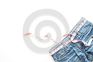 Flat lay of woman blue jeans with measuring-tape on white background, Diet and healthy lifestyle concept