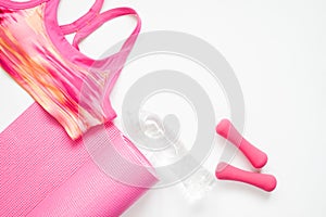 Flat lay of woman sport and yoga equipments in pink color on white background