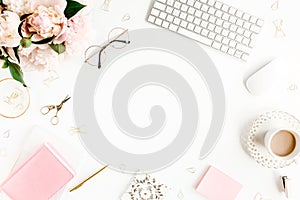 Flat lay women`s office desk. Female workspace with computer, pink peonies bouquet, accessories on white background. Top