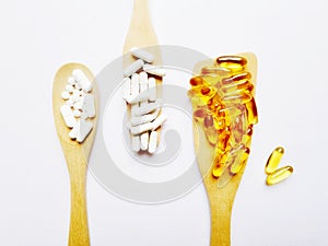 flat lay with wooden ladles containing vitamin and omega3 supplement capsules