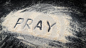 Flat lay of word PRAY written on white sand