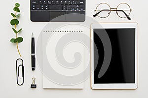 Flat lay work place. White office desk table with laptop, clips, glasses, notebook and pen. Top view with copy space