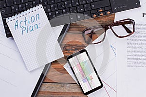 Flat lay workspace with smartphone, eye glasses, notebook, keyboard.