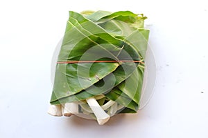 flat lay of Young galangal roll and wrapped in green leaves banded with rubber bands isolated on white background