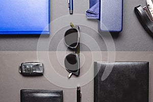 Flat layer of men accessories, sunglasses, agenda, car key, pen over two creative background