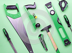 Flat layout: a set of hand tools for construction and repair on a green background.