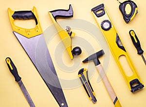 Flat layout: a set of hand tools for construction and repair on a yellow background.