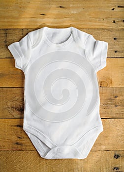 Flat mockup of a white unisex bodysuit for a boy and a girl on a wooden background. Layout for the design and placement of prints