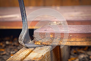 Flat pry bar lifting of a rotten plank off a deck construction