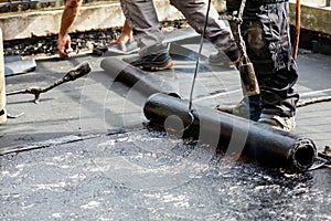 Flat roof installation. Heating and melting bitumen roofing felt