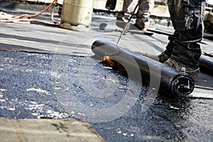 Flat roof installation. Heating and melting bitumen roofing felt