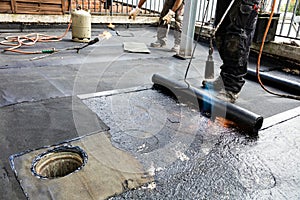 Flat roof installation. Heating and melting bitumen roofing felt