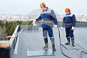 Flat roof installation. Heating and melting bitumen roofing felt