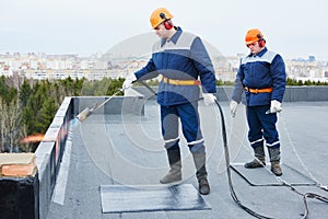 Flat roof installation. Heating and melting bitumen roofing felt photo