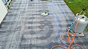 Flat roof repair: roofer welds roof waterproofing. Roof renovation with gas burner