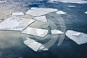 Flat slabs of ice floating on blue clear water